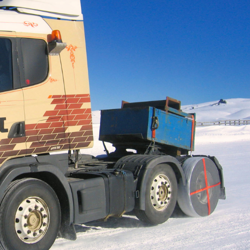 AutoSock tire sock mounted on truck wheels, driving on snow in winter landscape