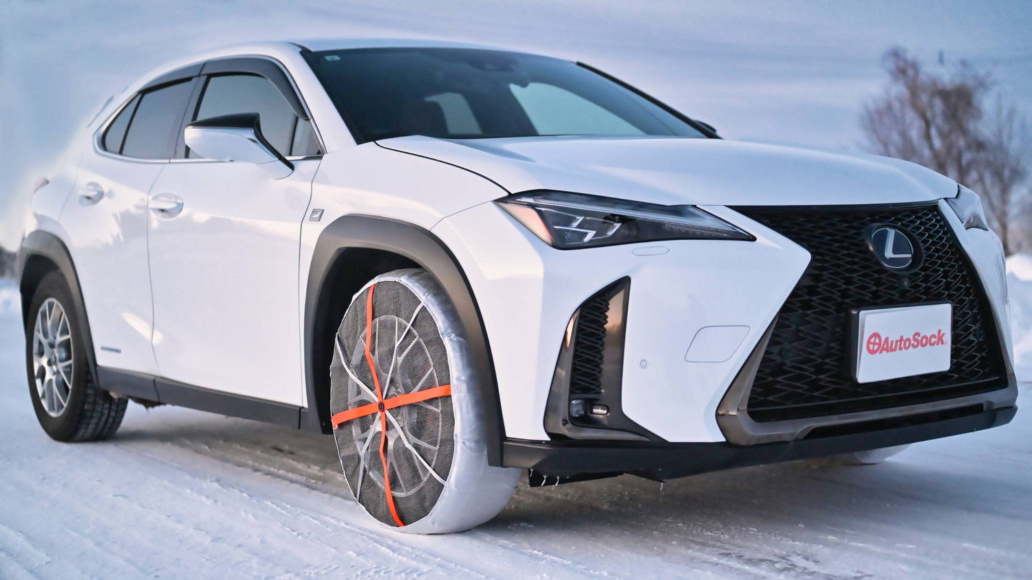 White Lexus SUV on a snowy road with snow socks installed on front tyres