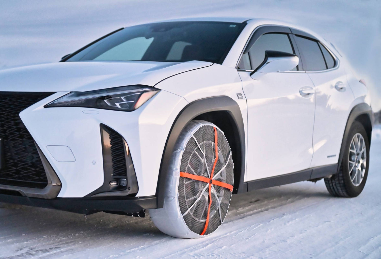 White Lexus SUV on a snowy road with snow socks installed on front tyres