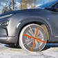 AutoSock textile snow chains mounted on front wheels of a passenger car, standing on snow in woods